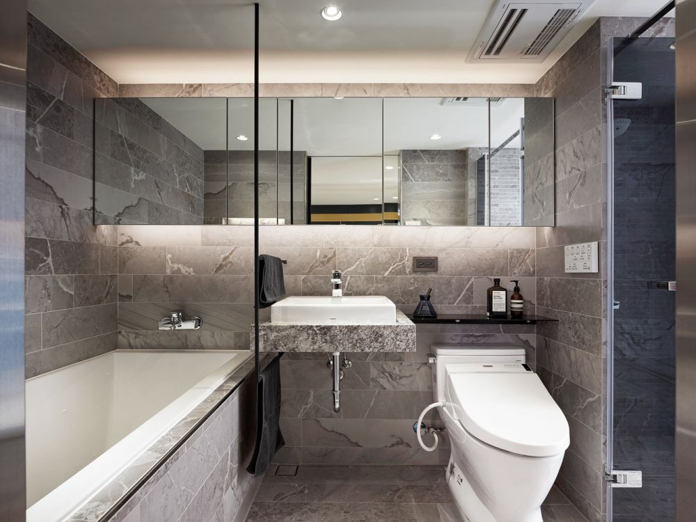 The bathroom has this stone-inspired look, with large backlit mirrors and a warm and welcoming vibe