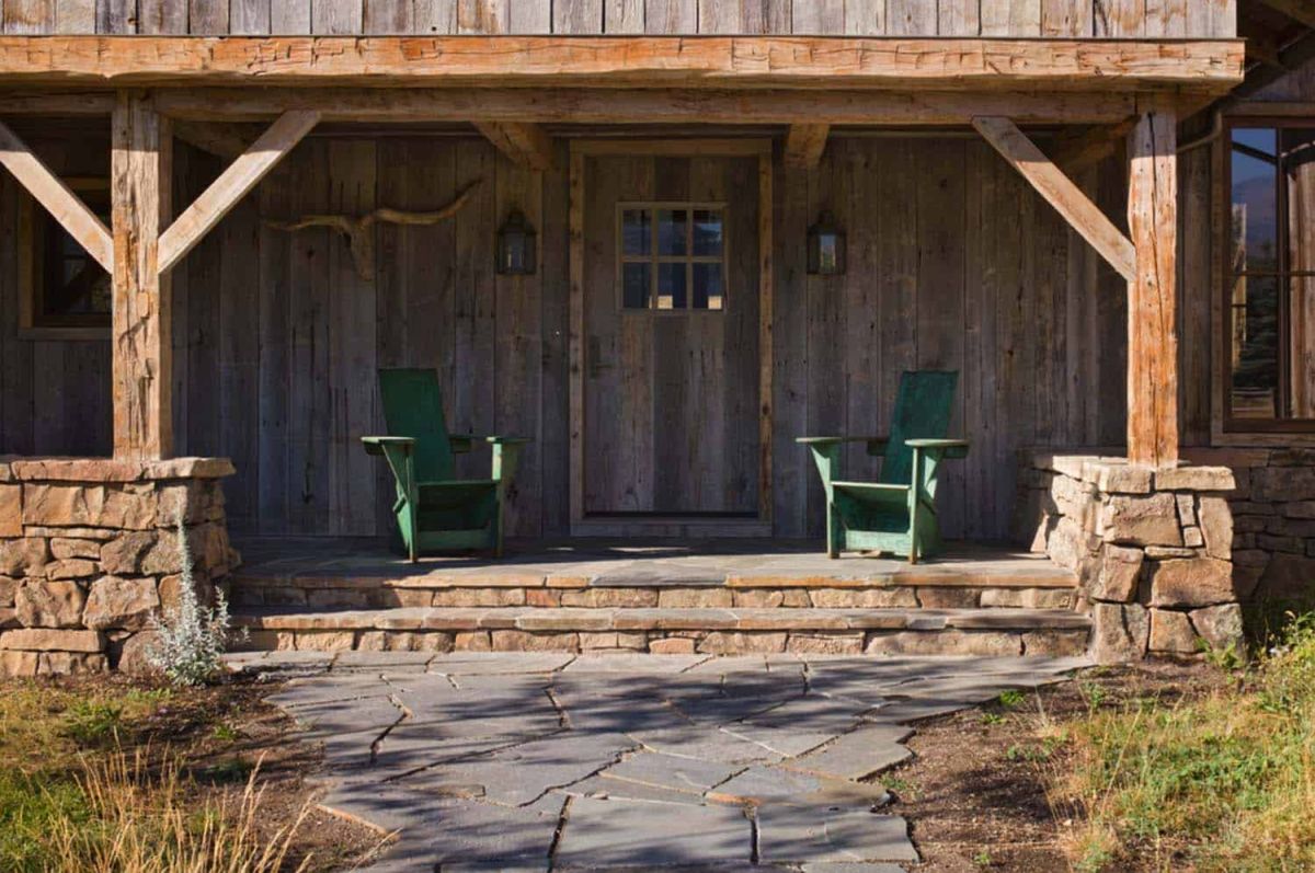 A covered patio built out of wood and stone frames the barn's new extension