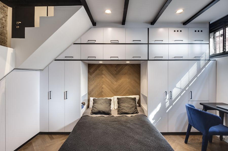 The bed is framed by custom-built white cabinetry which offers lots of storage