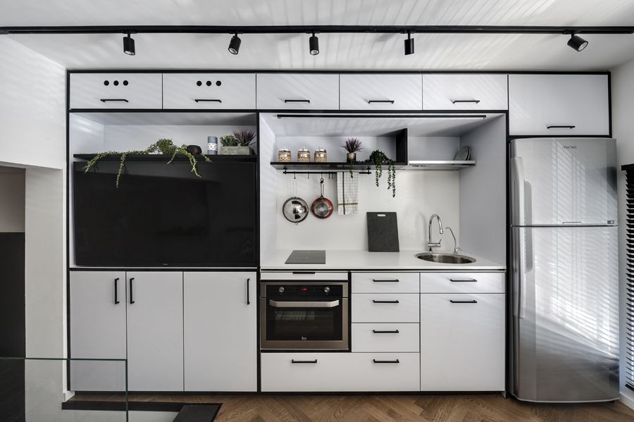 The storage wall includes the kitchen module as well as a large built-in TV