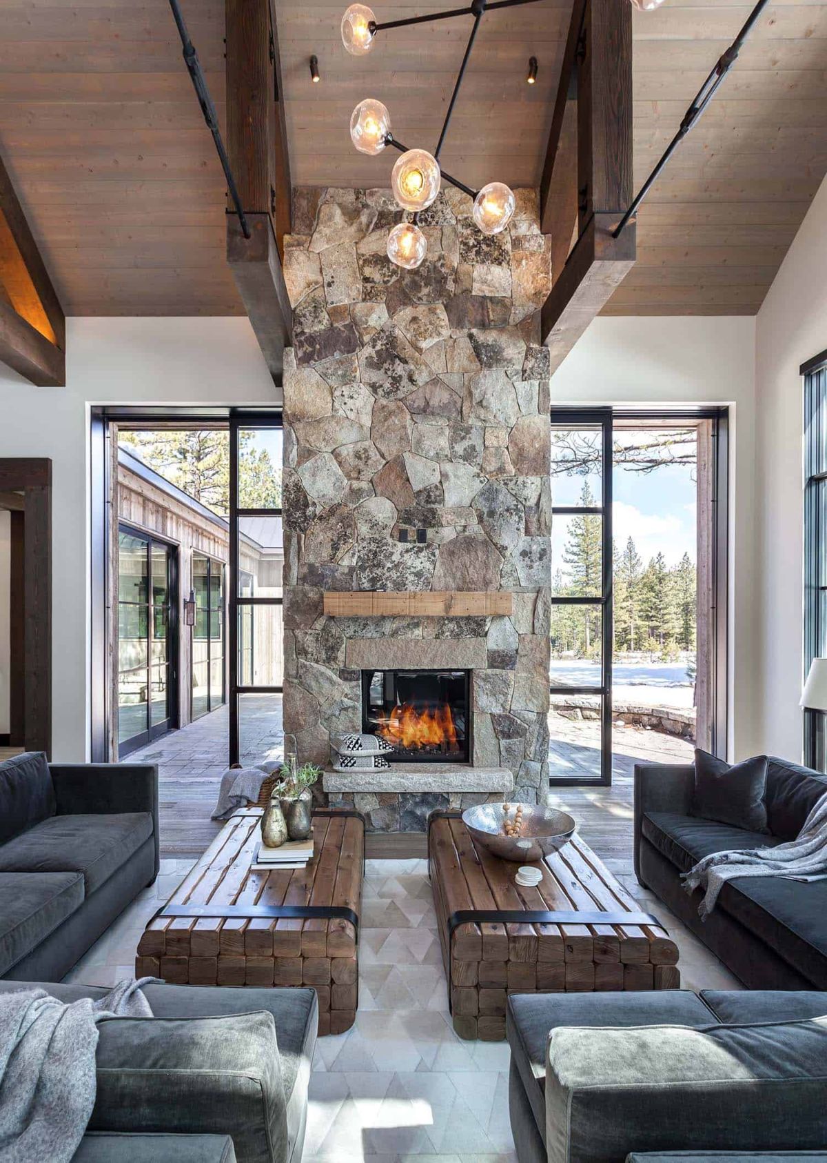 The floor-to-ceiling stone fireplace in the living room has sliding doors on either side which disappear inside it when open