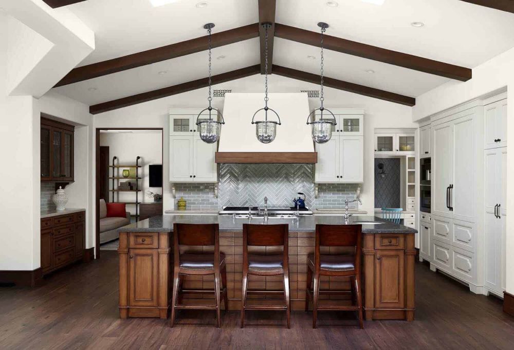 Exposed wooden beams on the kitchen ceiling create a cozy vibe and complement the floors and the island