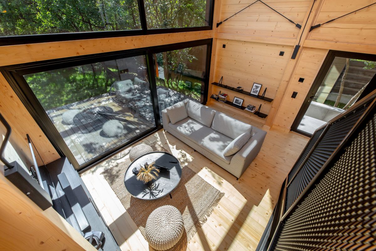 Large sliding doors open the living room towards a deck, inviting guests to celebrate nature