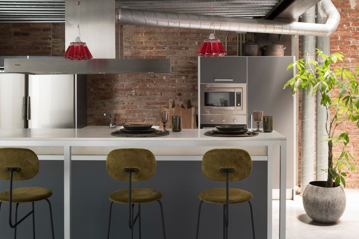 The kitchen features subdued colors and simple materials and has a modern-industrial vibe