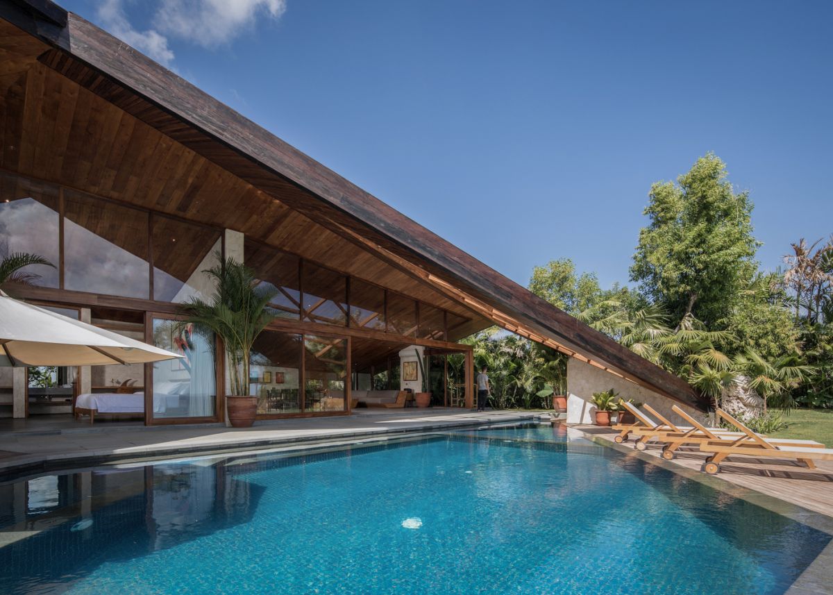 The living areas open up to a covered patio and a swimming pool, partially covered by the unique roof